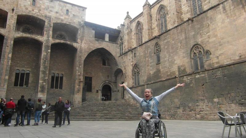 woman in wheelchair smiling with arms outstretched