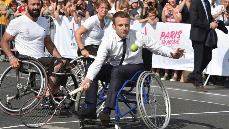 man in suit plays tennis in wheelchair