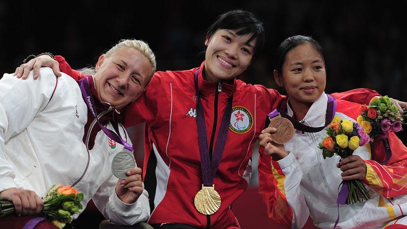 three women with medals standing on a podium