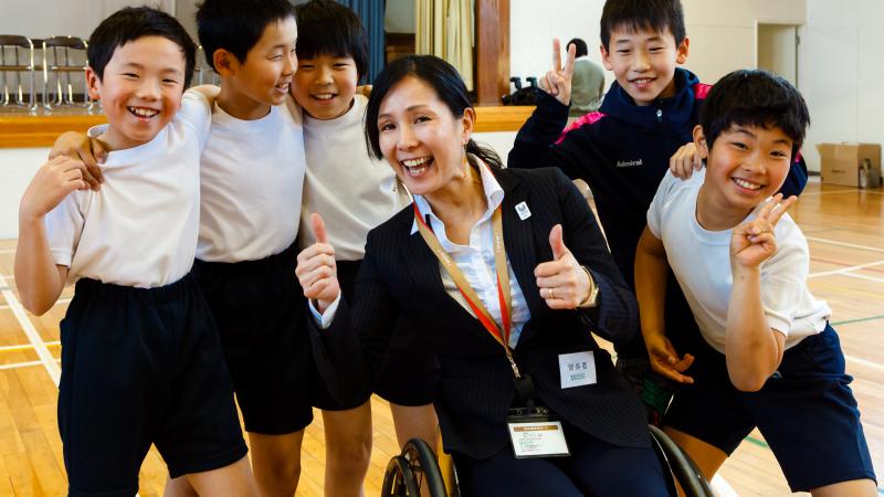 A group of children pose with a wheelchair athlete