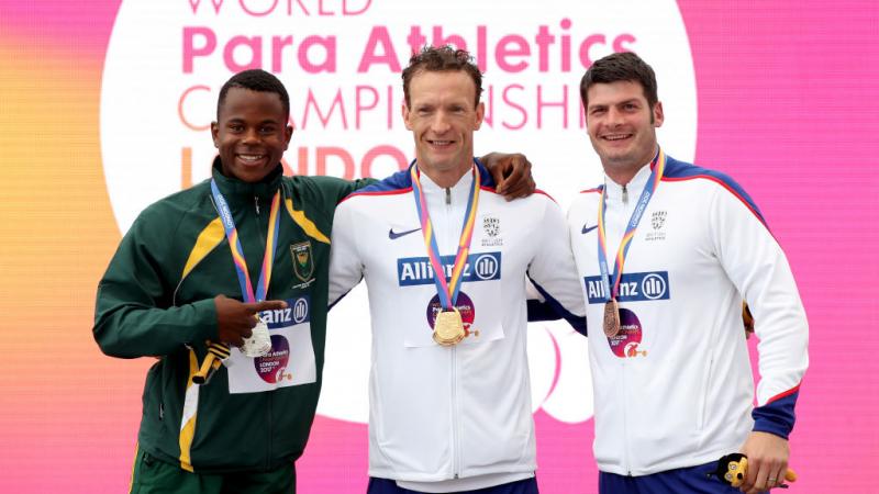 three men stand on the podium with their medals