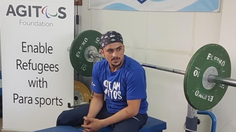 a male Para powerlifter sits on his bench