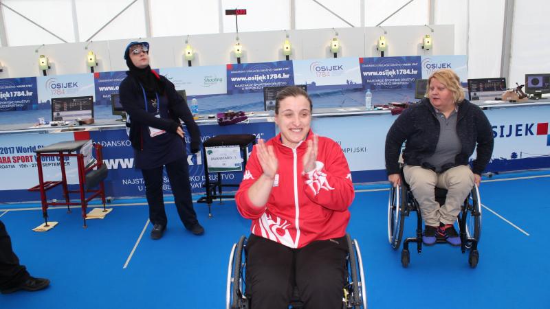 Female shooter in wheelchair smiles after winning