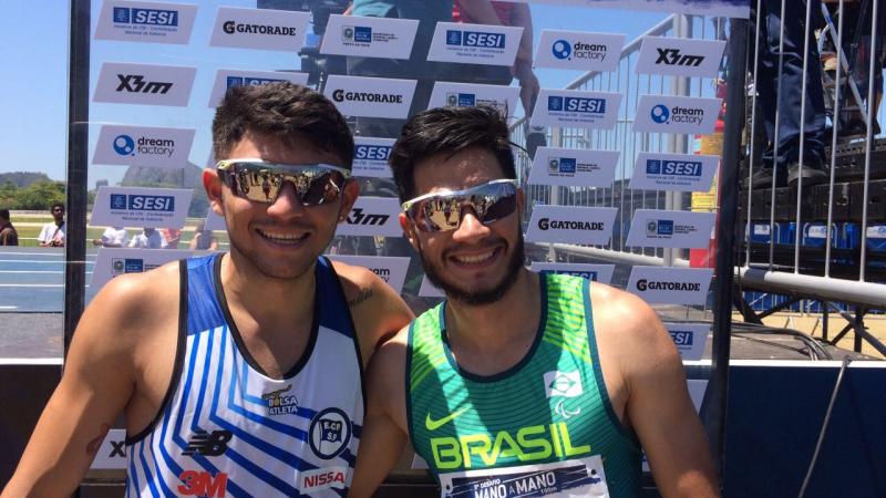 Two Brazilian para athletes smile with their arms around eachother