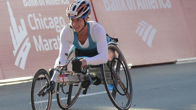 a female wheelchair racer celebrates crossing the line