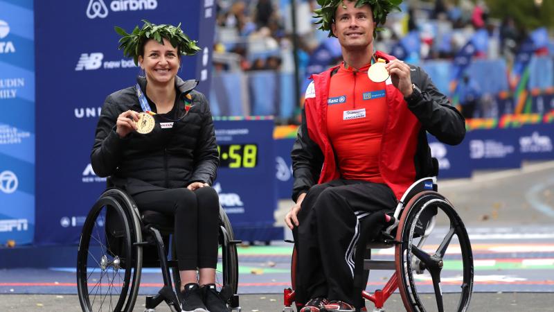 a male and female wheelchair racer celebrate with their gold medals