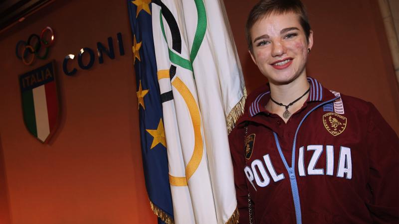 an female Para athlete smiles in front of an Italian flag