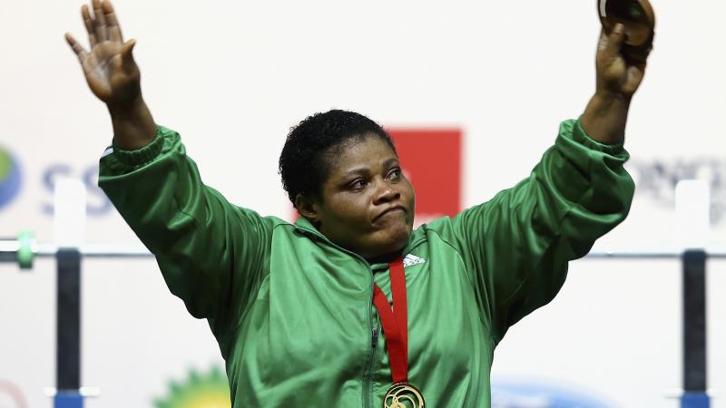 a female powerlifter raises her arms in celebration