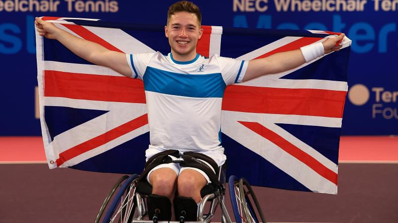 a male wheelchair tennis player holds up the Union Jack