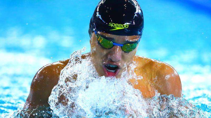 a male Para swimmer takes a breath out of the water between strokes