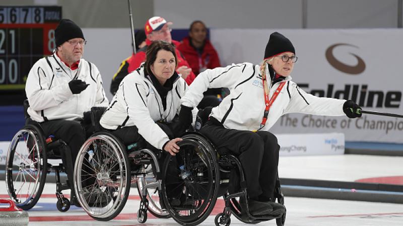 a female wheelchair curler pushes the stone across the ice