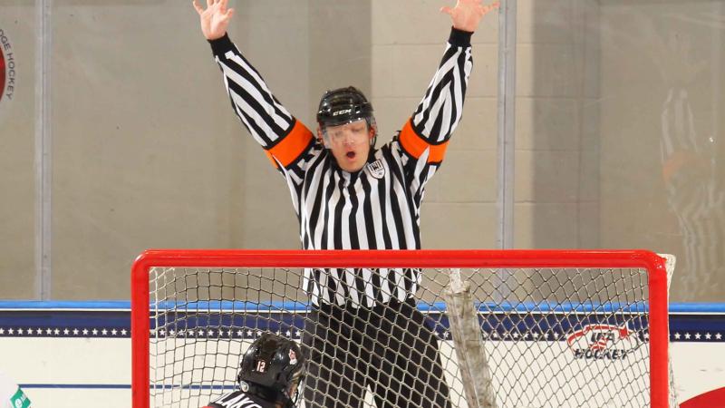 a male Para ice hockey referee throws his hands up to signal