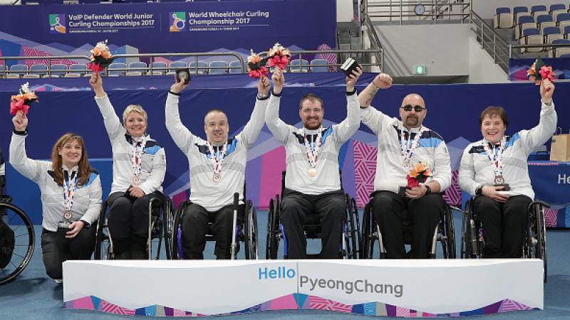 a group of wheelchair curlers celebrate with their medals
