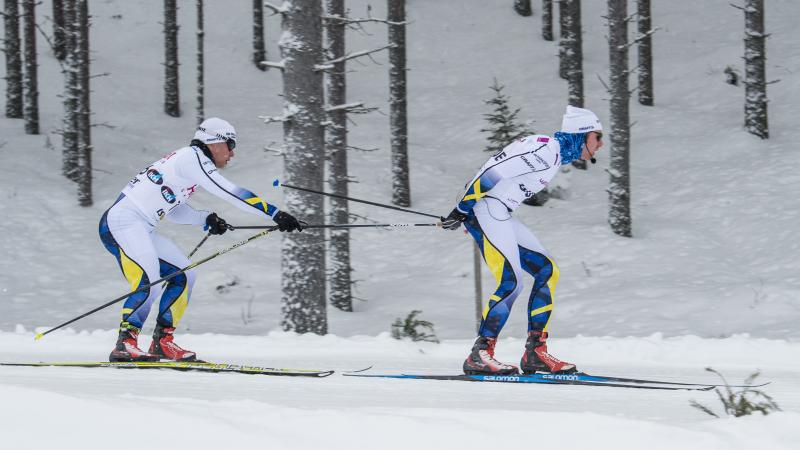 a male Nordic skier and his guide mid-race