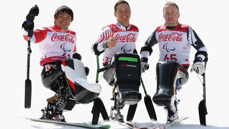 three male sit skiers celebrating on the snow 