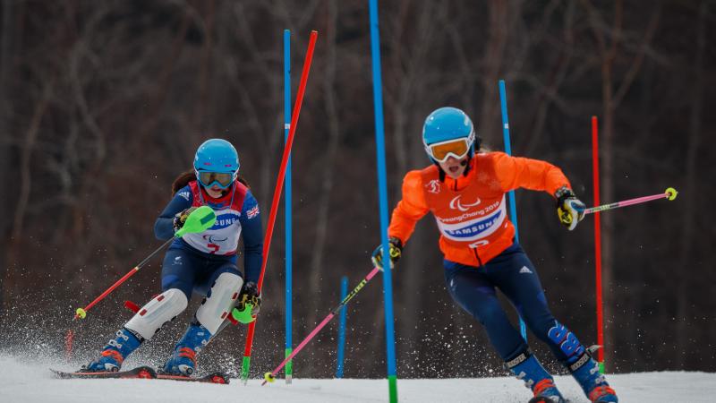 a female vision impaired skier and her guide go through the slalom gates
