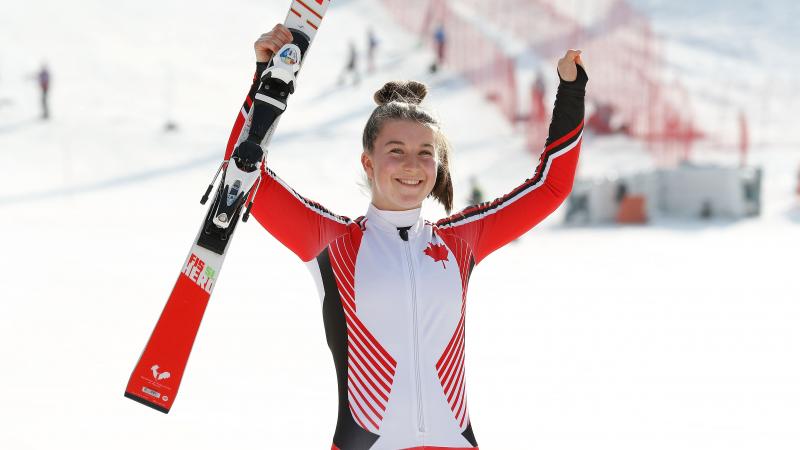 a female Para skier raises her arms in celebration