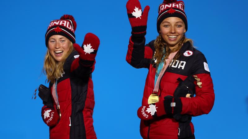 two female Nordic skiers wave from the podium