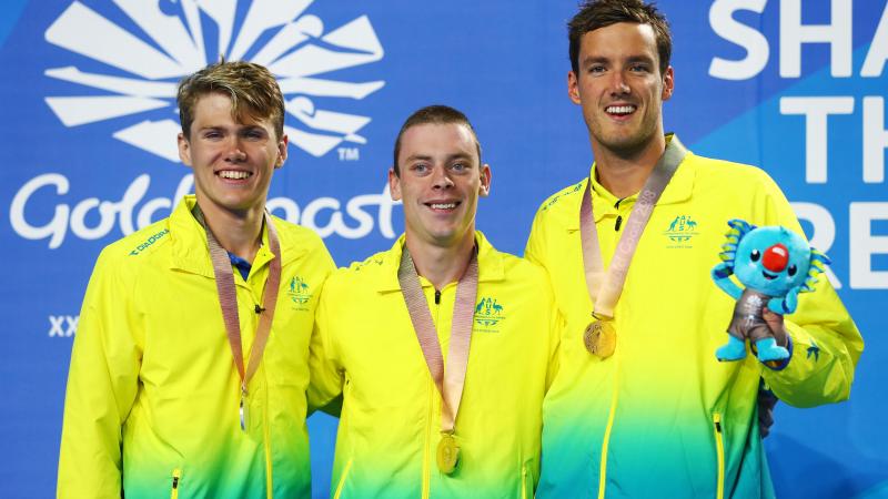 three male swimmers on the podium