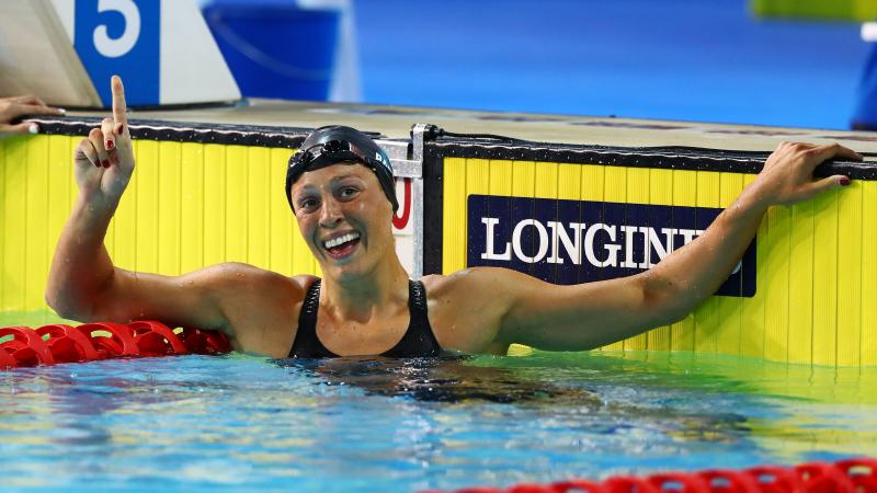 a female swimmer raises her arm in celebration in the pool