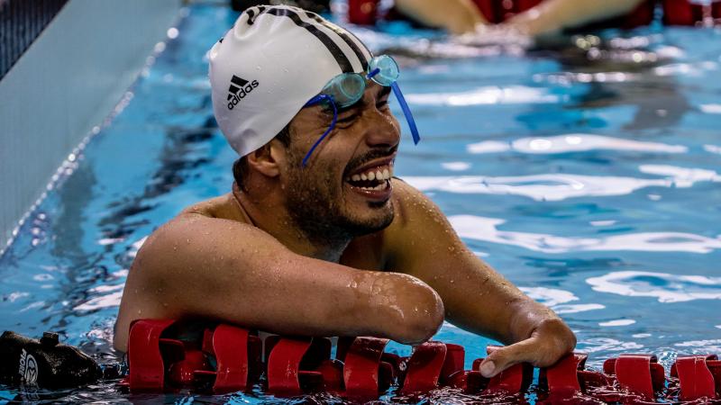 a male Para swimmer laughs in the pool