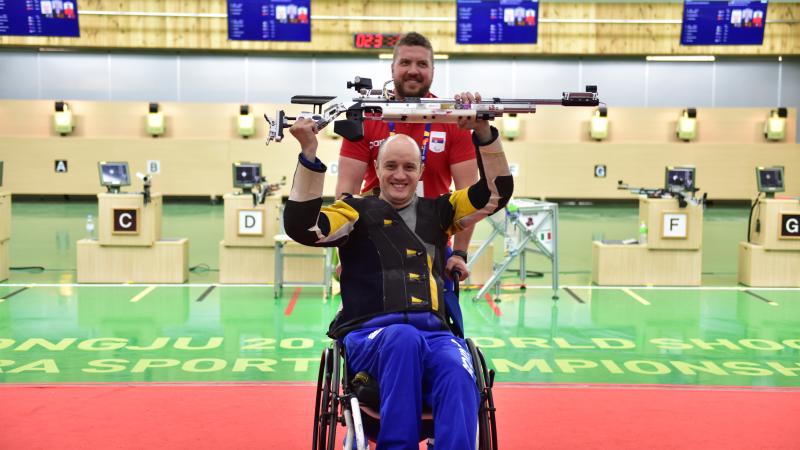 a male Para shooter and his coach celebrate 
