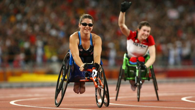 a female wheelchair racer celebrates after the finish line