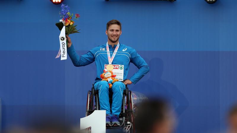 Person in a wheelchair on a podium holding flowers 