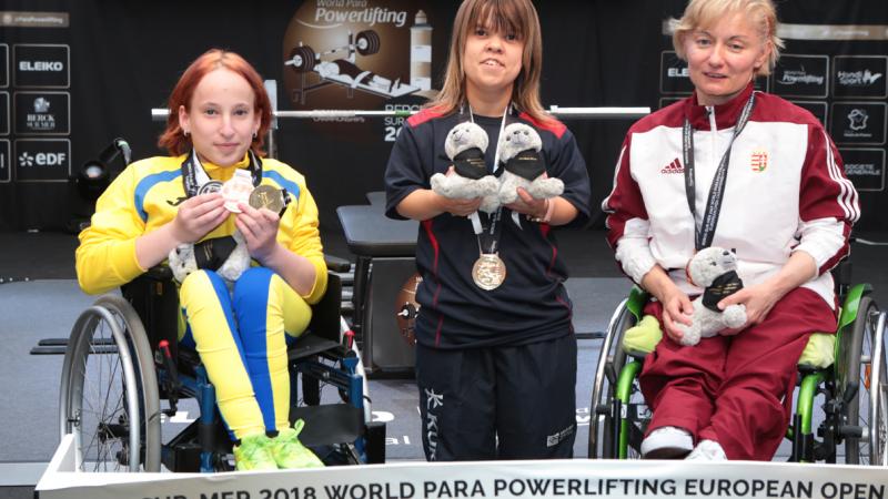 three female powerlifters on the podium