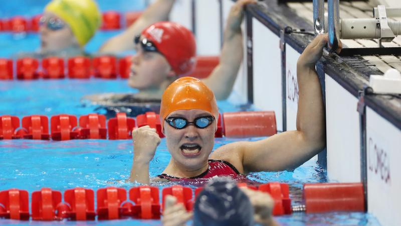 a female Para swimmer punches in the air in the pool