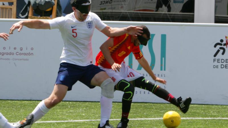 two male blind footballers battling for the ball 
