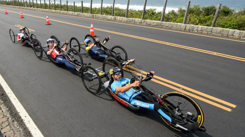 a group of male Para cyclists race along the road