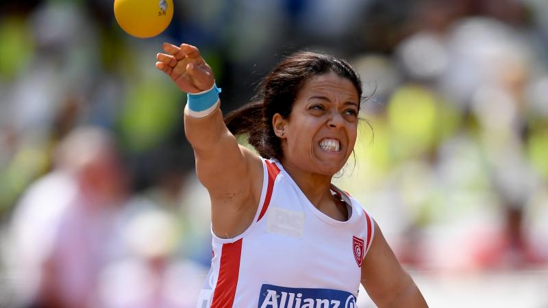 a female Para athlete of short stature throws a shot put