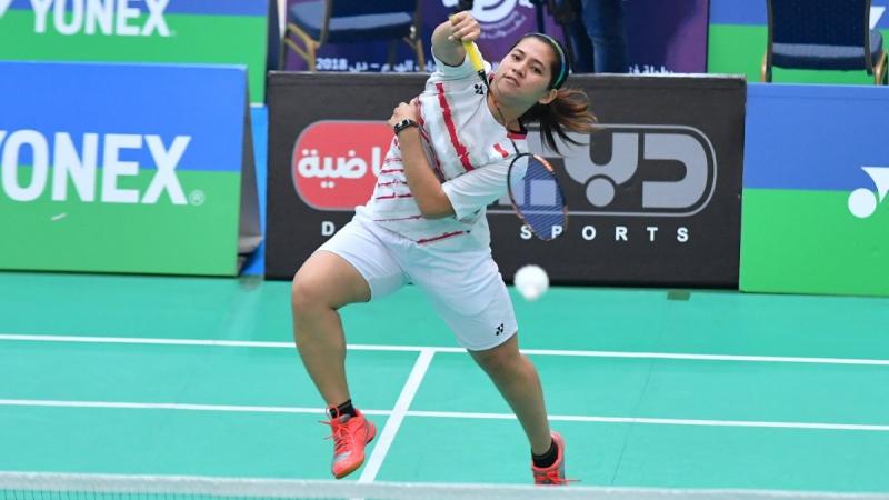 Female badminton player jumps to hit a birdie