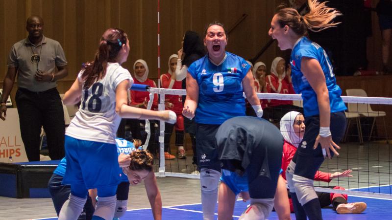 three female Italian sitting volleyball players celebrate on the court