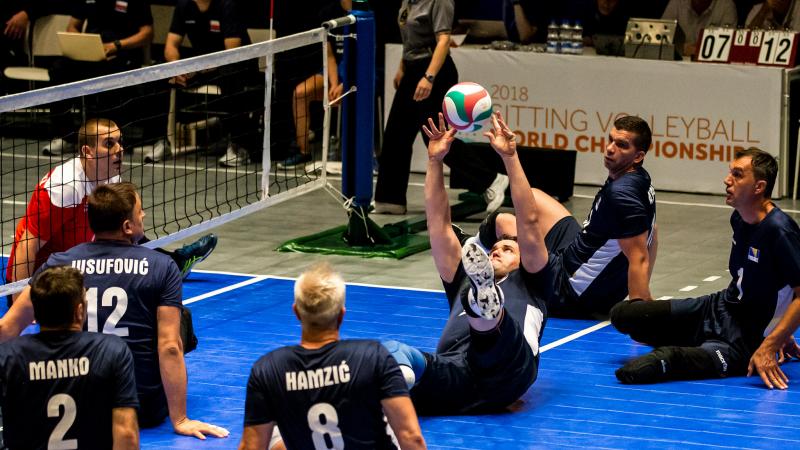 a group of Bosnian male sitting volleyball players working to get the ball back over the net