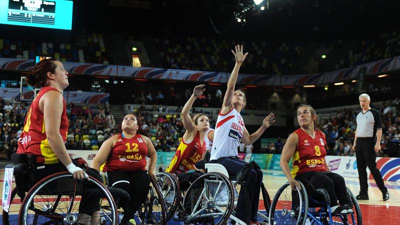a group of female Spanish wheelchair basketballers fighting for the ball on the court