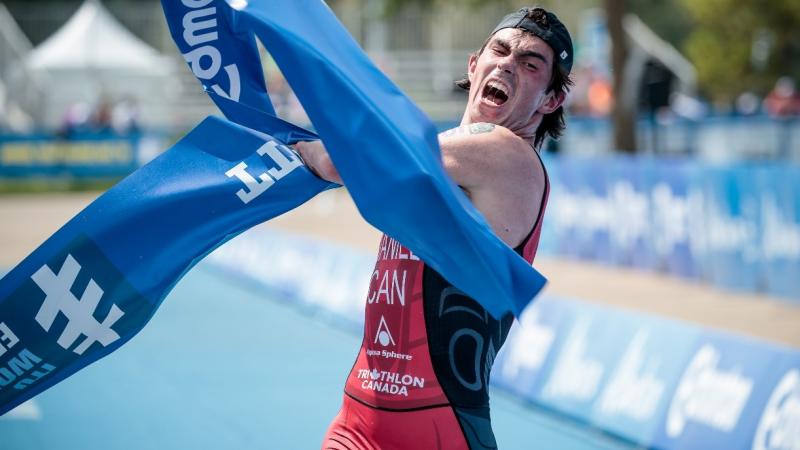 male Para triathlete Stefan Daniel rips the tape at the finishing line as he crosses to win the race