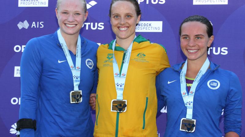 Three women with medals smiling