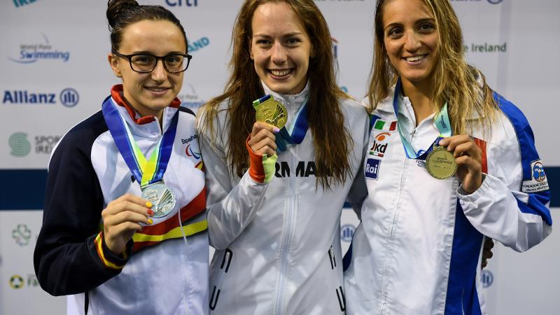 three female Para swimmers, with Naomi Maike Schnittger in the centre, holding up their medals