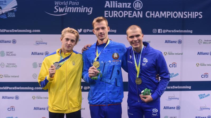 three male Para swimmers including Ihar Boki in the middle, on the podium holding their medals