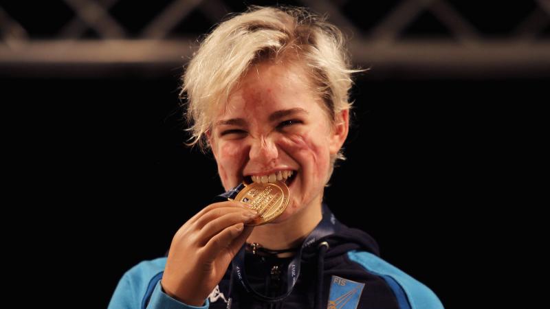 female wheelchair fencer Beatrice Vio bites a gold medal and smiles
