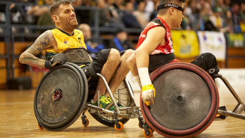 male wheelchair rugby player Ryan Scott chases another player with the ball