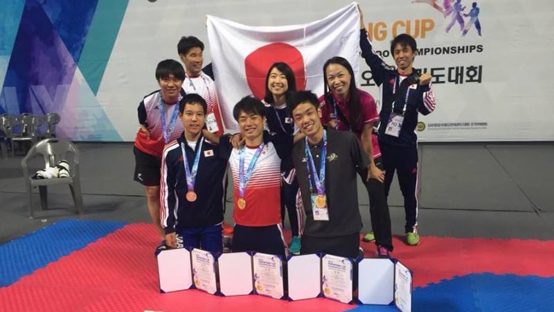 a group of Japanese Para taekwondo fighters with their medals and a Japan flag