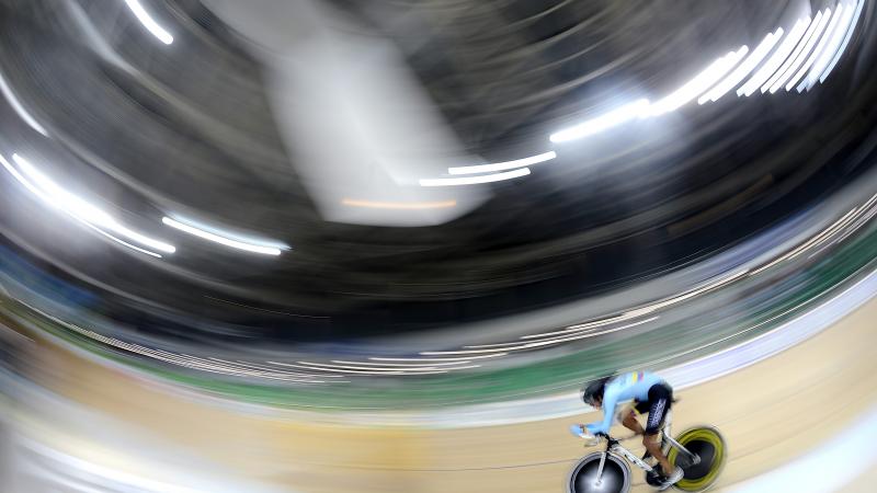 Man on track cycle rides around a velodrome
