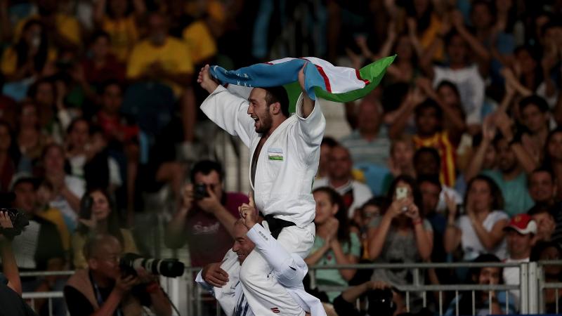 A man carrying Uzbekistan's flag on another man's shoulder
