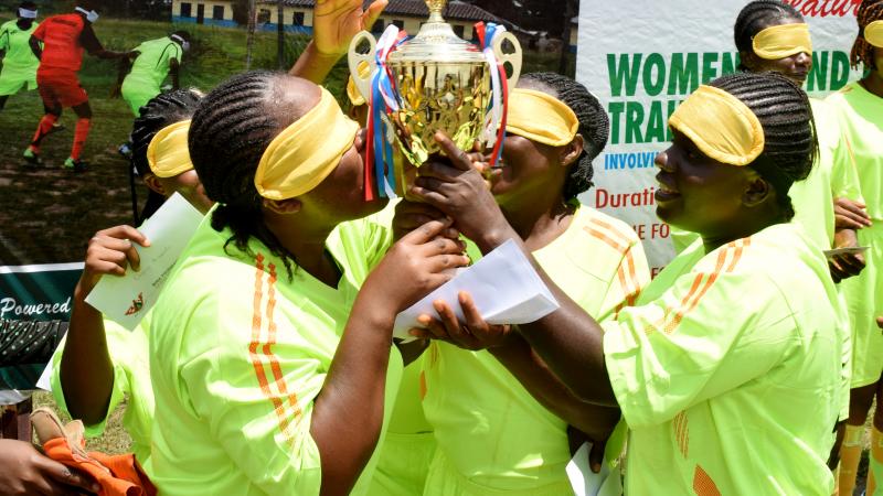 four female blind footballers kissing a trophy