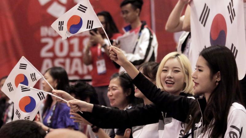a group of men and women waving South Korean flags