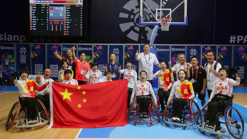 a female Chinese wheelchair basketballer shields the ball from another player