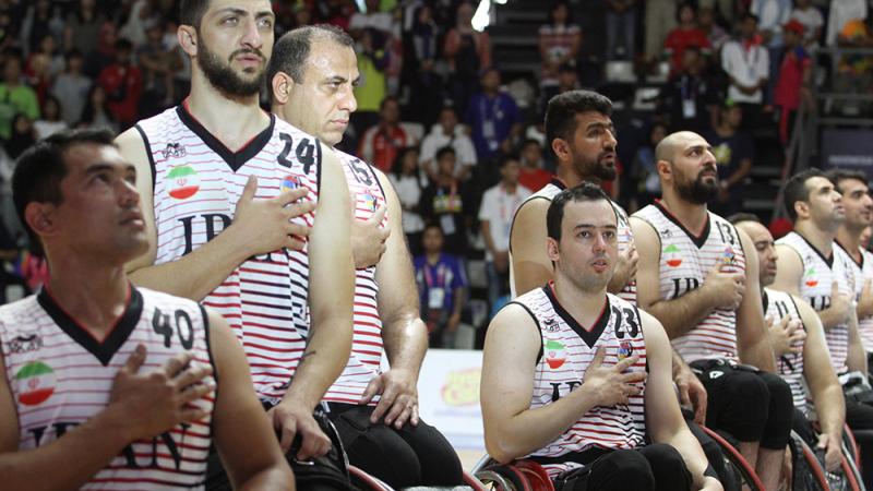 male wheelchair basketball players with Iran on their shirt holding their hands over their heart and singing